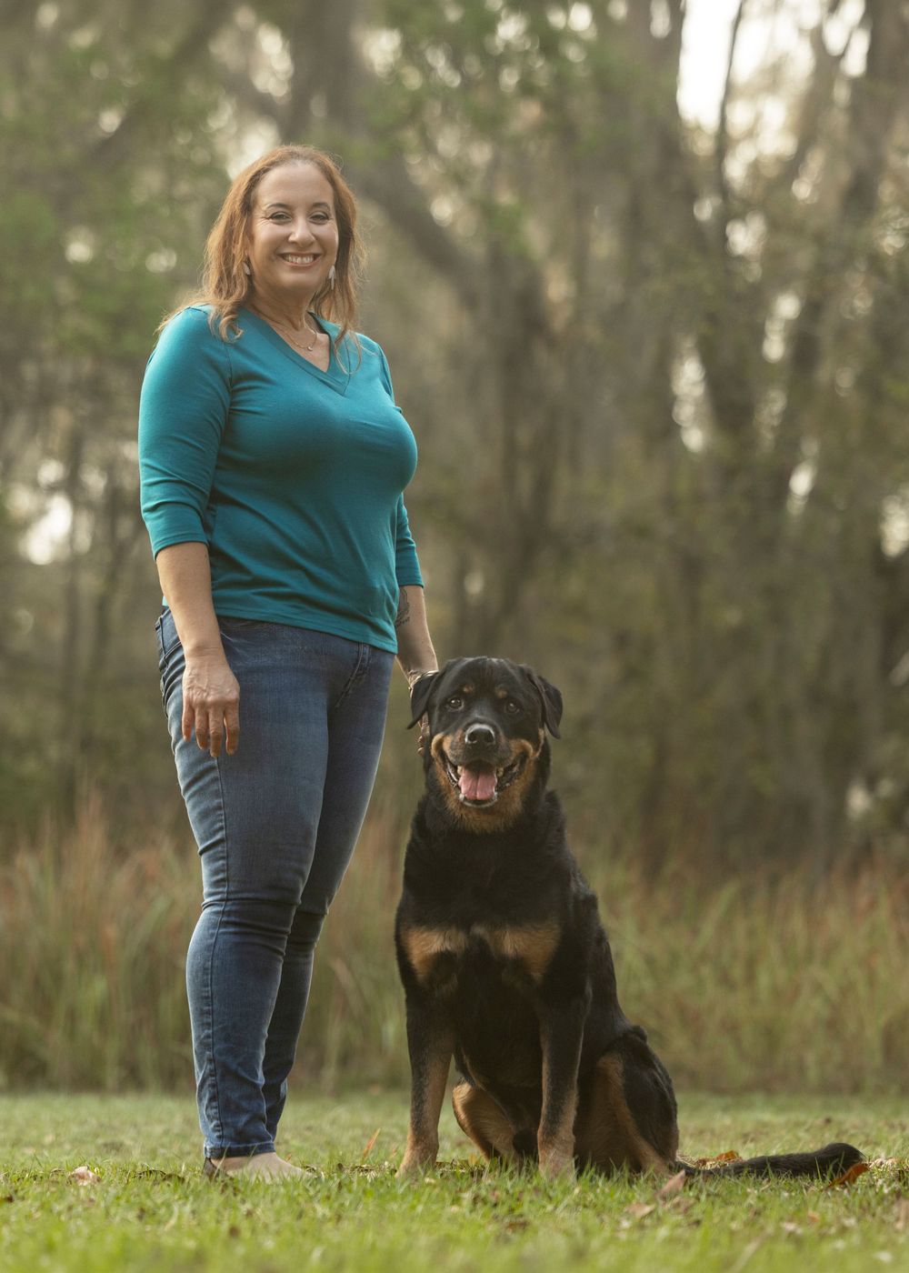 woman standing with her rottweiler in the park