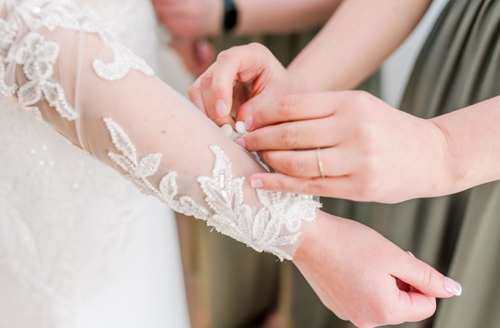 Close-up of delicate lace sleeve details on a wedding dress with intricate embroidery patterns.
