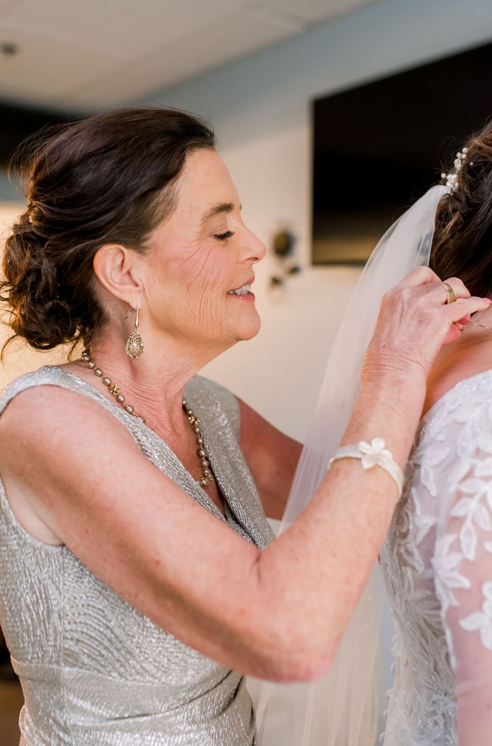 A tender moment during wedding preparations as final adjustments are made to a bridal veil.