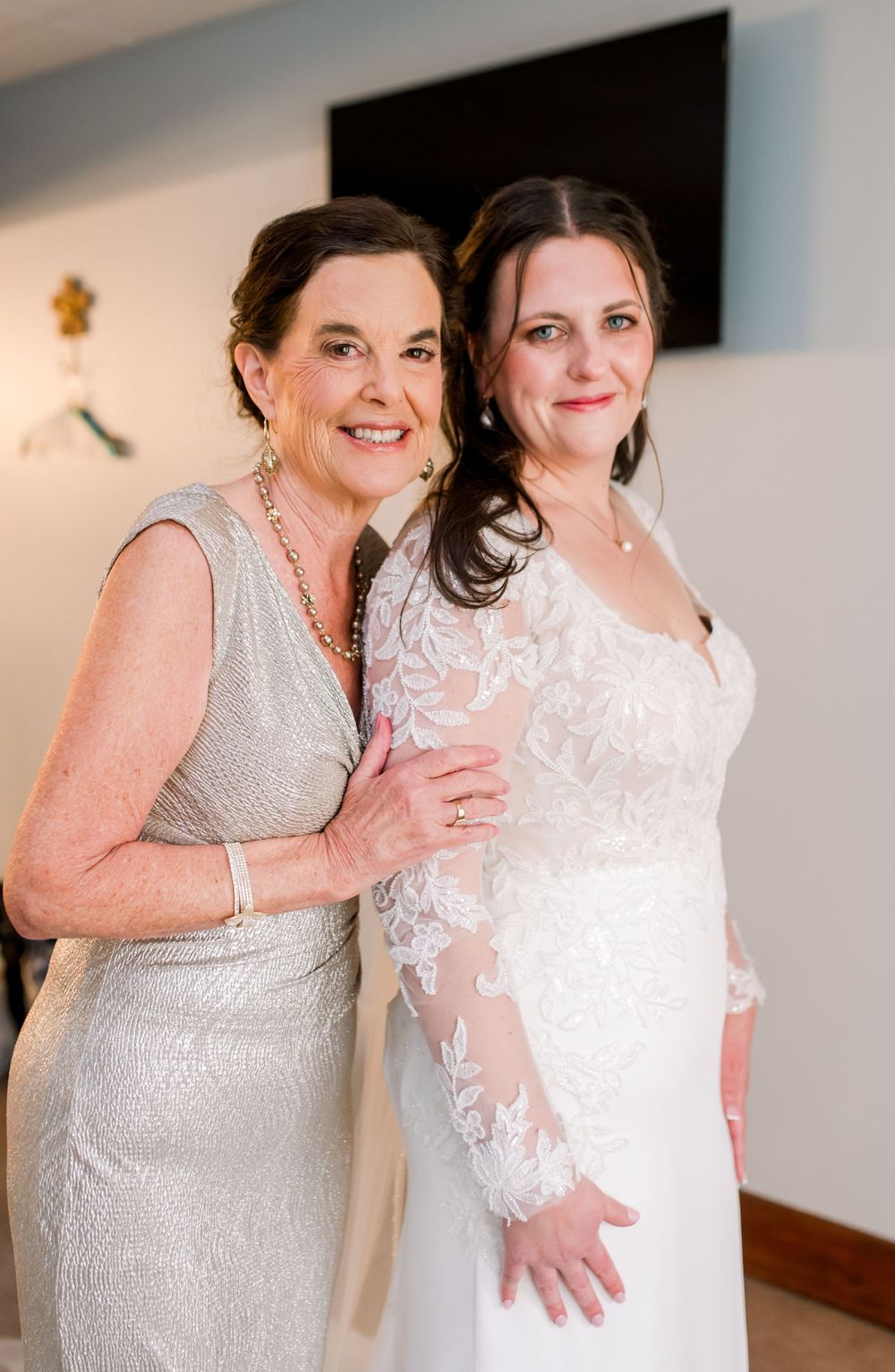 Two women in formal attire sharing joyful moment at wedding celebration.