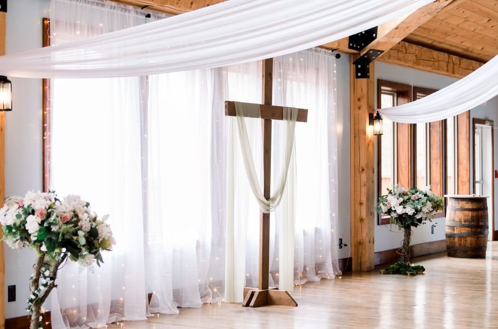 Elegant wedding venue interior with white draping and wooden beam ceiling creates a romantic atmosphere.