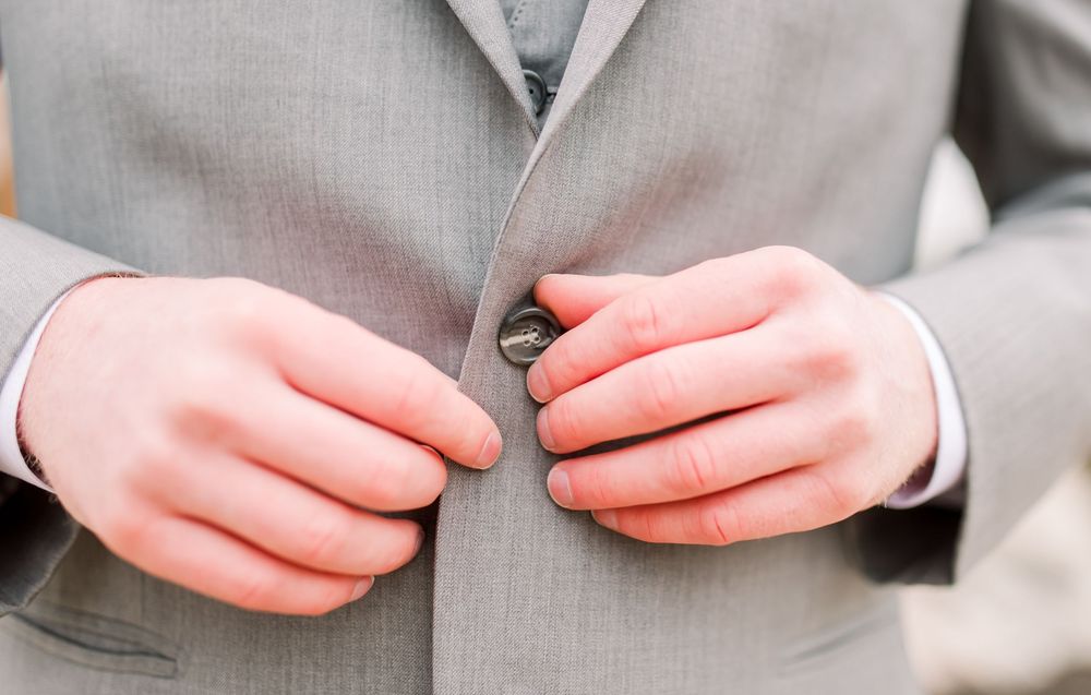 Close-up details of grey suit buttons and formal attire.