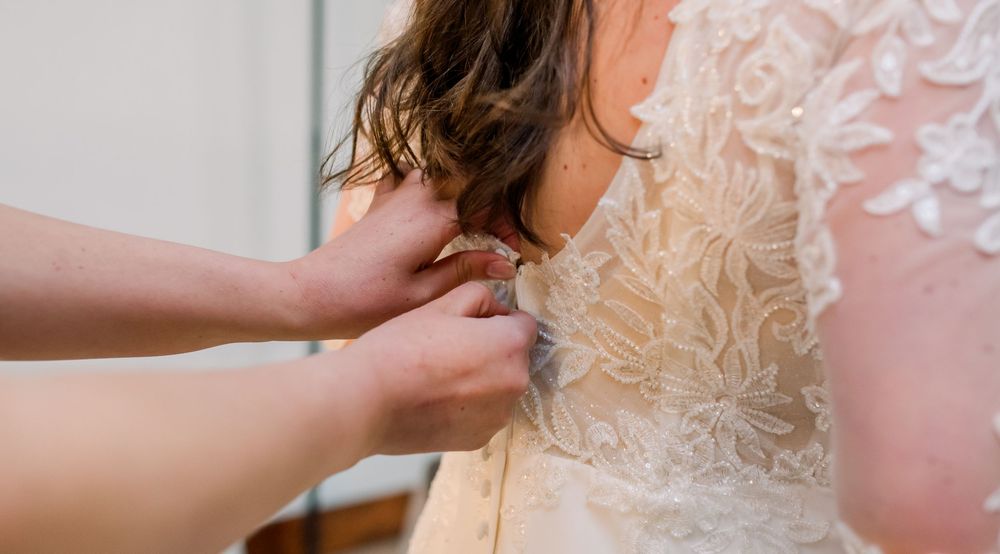 Close-up detail of intricate lace pattern on a wedding dress with delicate floral embellishments.