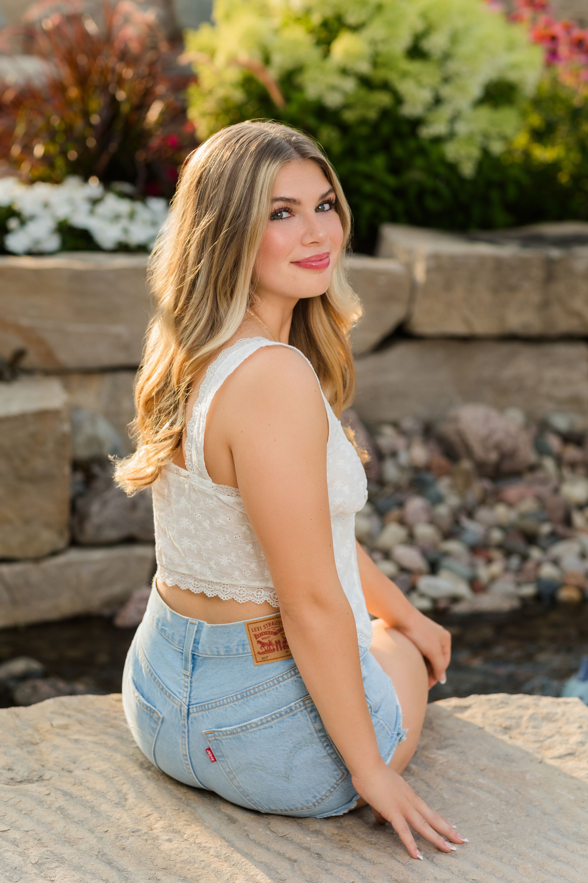 A series of outdoor portrait shots showing someone in a white lace top and denim jeans sitting on stone steps.