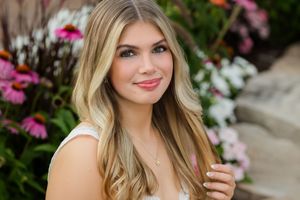 Professional outdoor portrait session with floral garden backdrop featuring pink and white blooms.