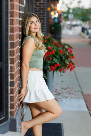 Urban fashion portraits against brick wall featuring sage green top and white ruffle skirt combinations.