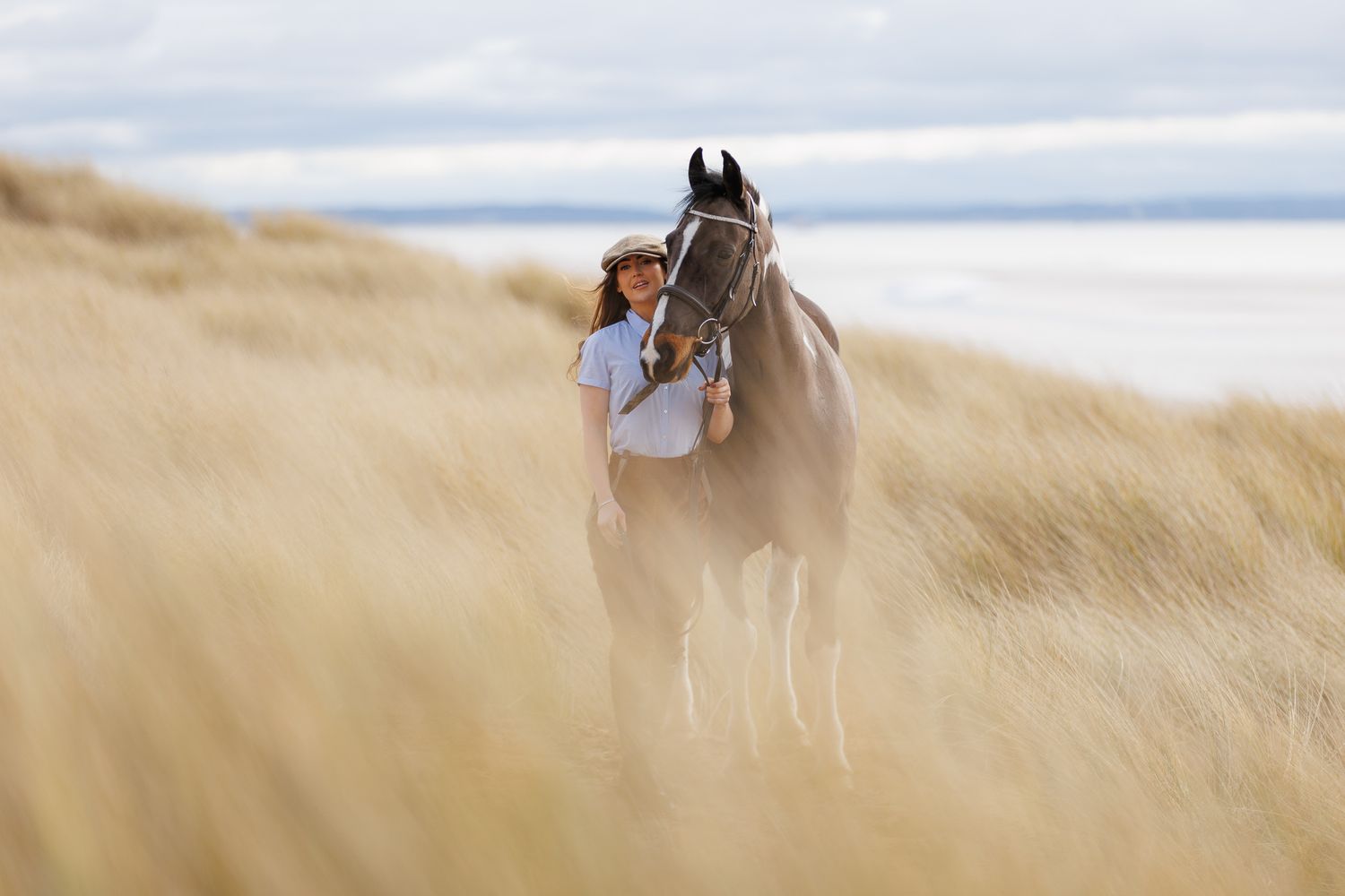 A beautiful black and white paint horse stands with a person on a sunny autumn day outdoors.