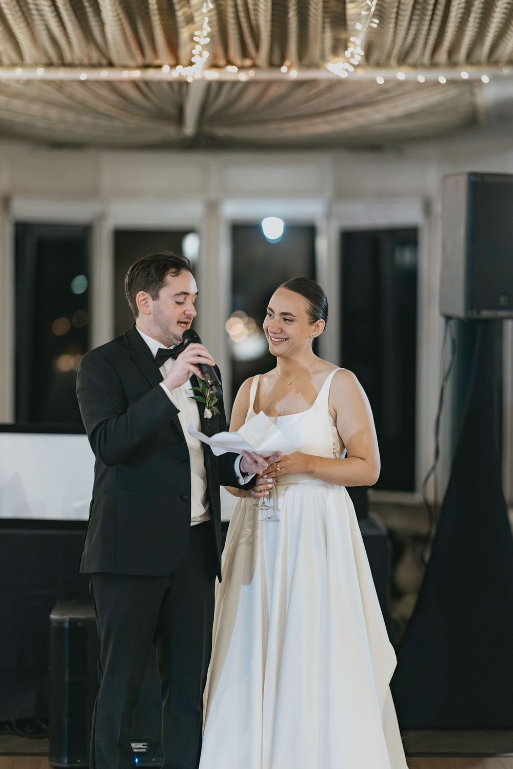 A couple shares a joyful moment during their first dance at a wedding reception under an ornate domed ceiling.
