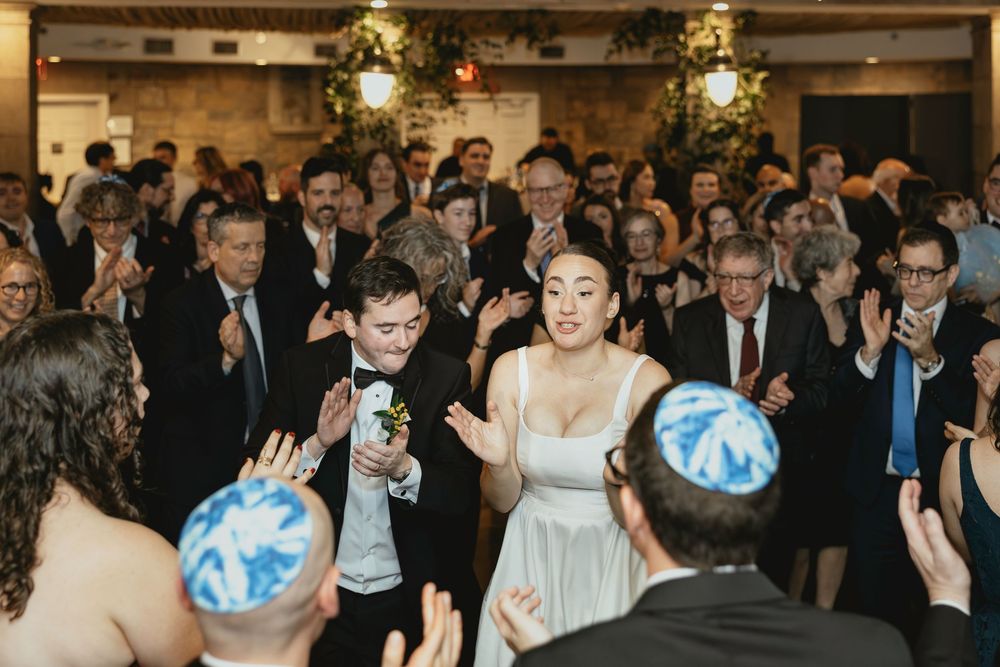 Wedding guests dance and celebrate on a crowded dance floor during an evening reception.