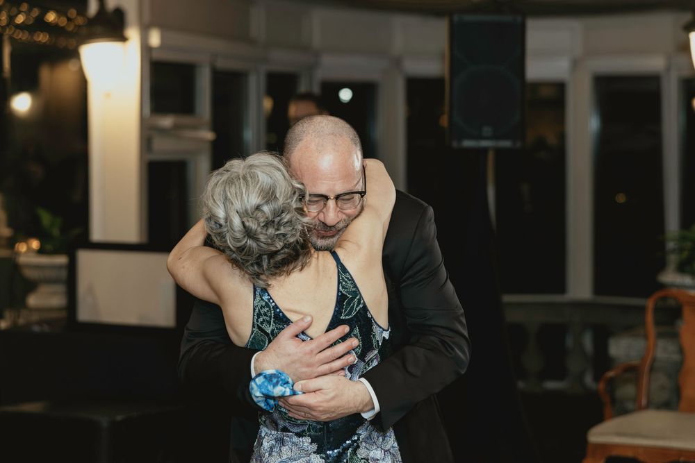 A couple shares a tender embrace during a romantic evening at a dimly lit venue.