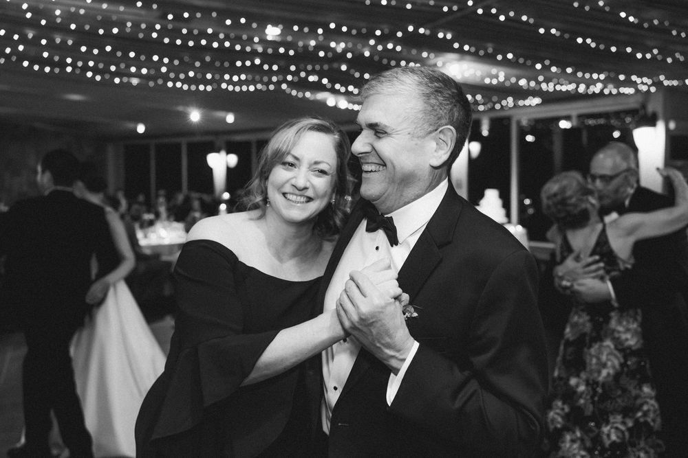 A couple dances together under twinkling string lights at an elegant evening reception.
