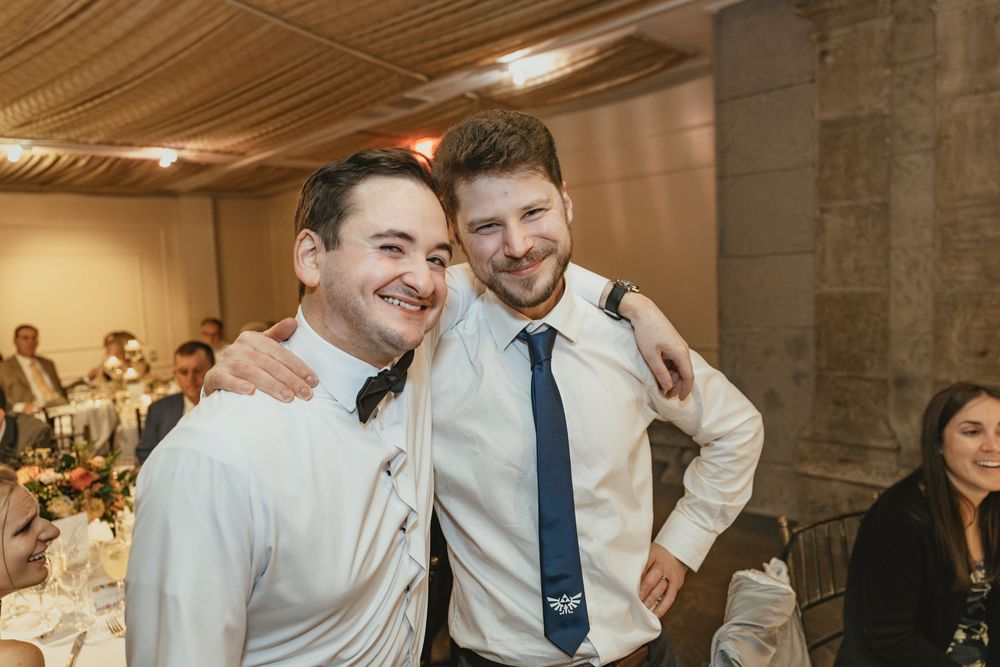 Wedding guests laughing and enjoying themselves at an indoor reception venue with warm lighting.