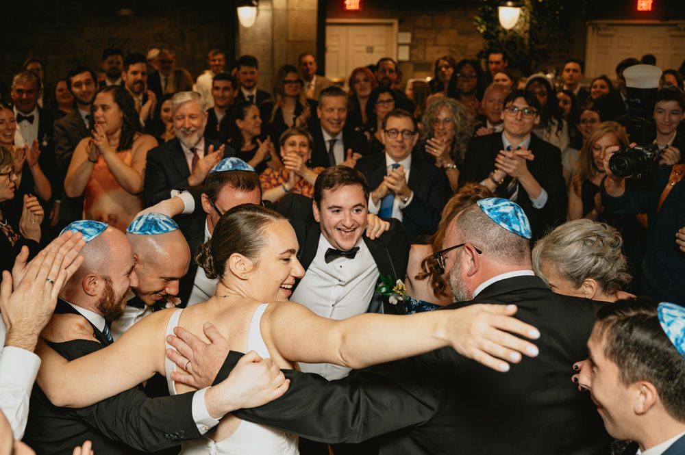 Wedding reception guests dancing and celebrating on a crowded dance floor.