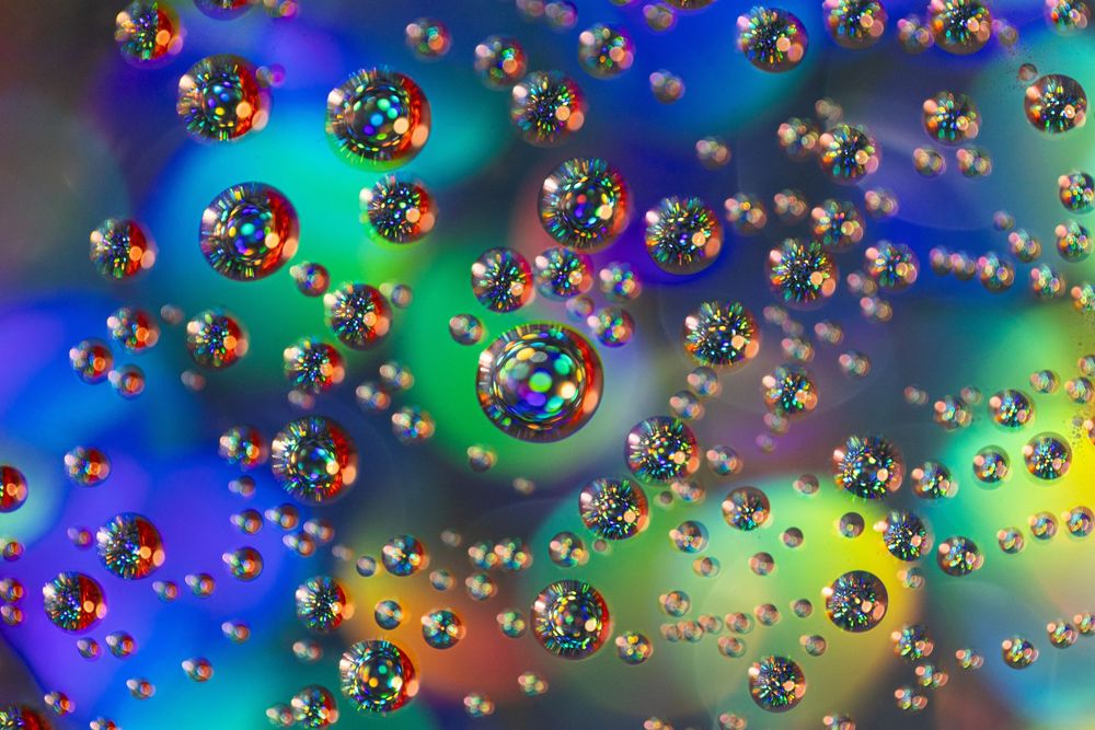 Abstract colorful bubbles floating against a vibrant blue and green background create a mesmerizing pattern.