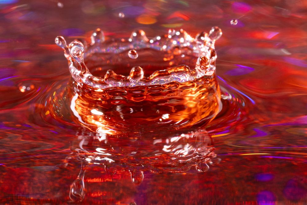 Water droplets creating dramatic red crown splashes against vibrant background.