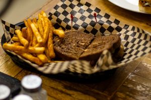A basket of golden french fries and a grilled sandwich served on checkered paper at Tommy's tavern during marketing photo session