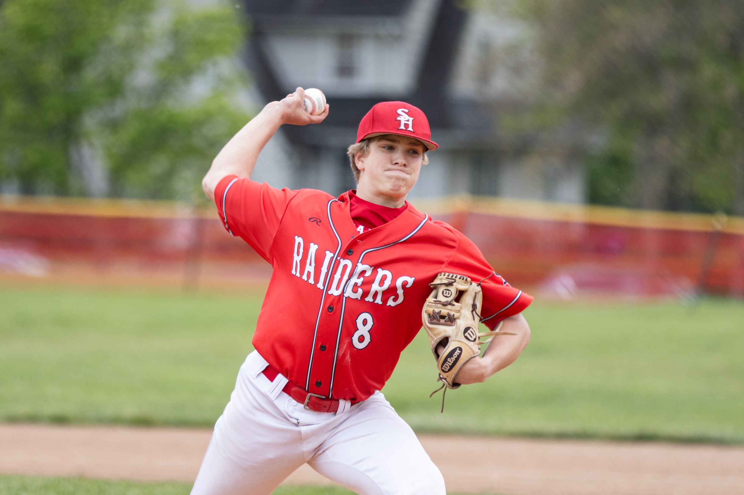 Baseball pitcher in red Raiders jersey number 8 winds up to throw during an outdoor game.