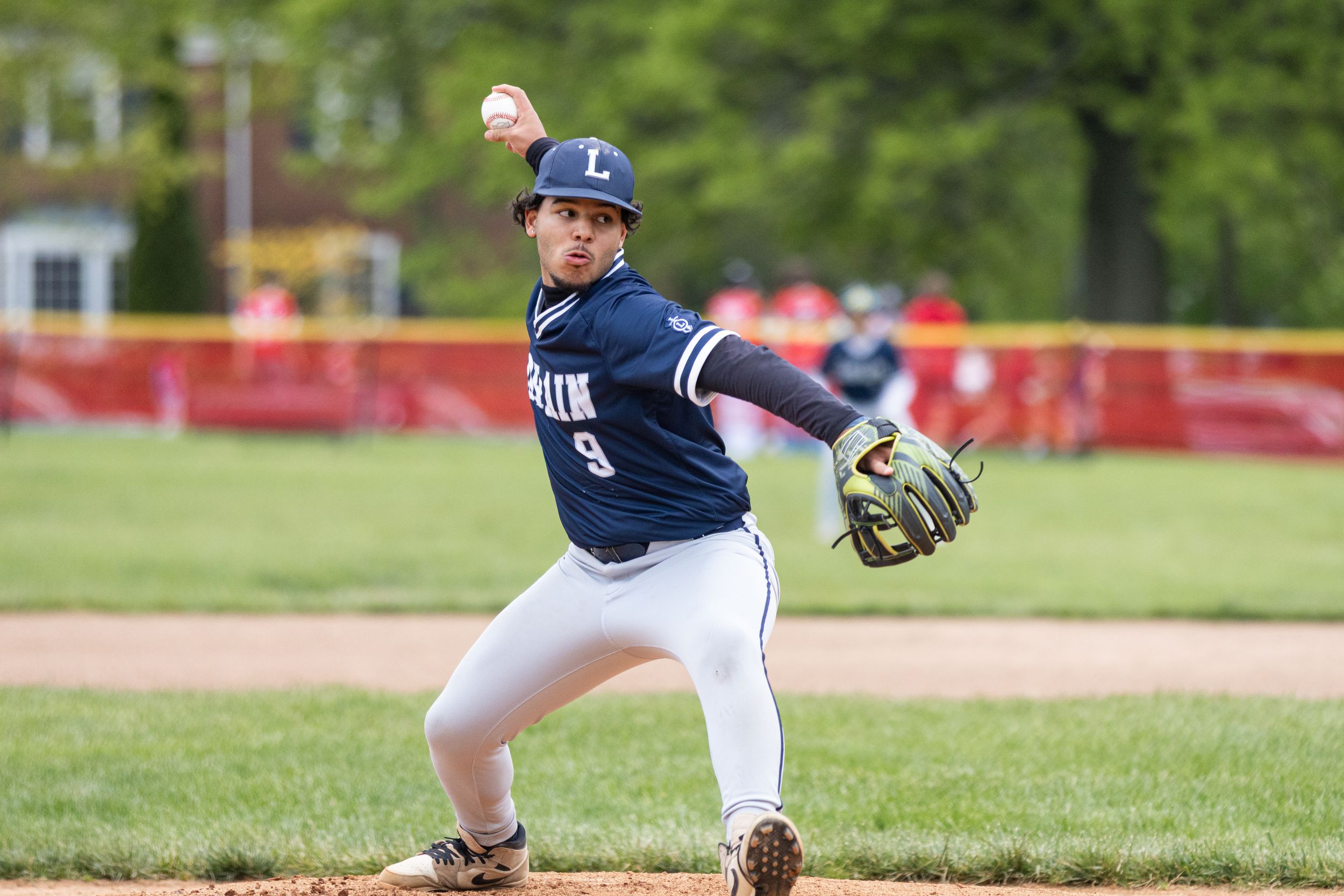 Baseball pitcher in navy uniform number 9 winds up to throw during an outdoor game.