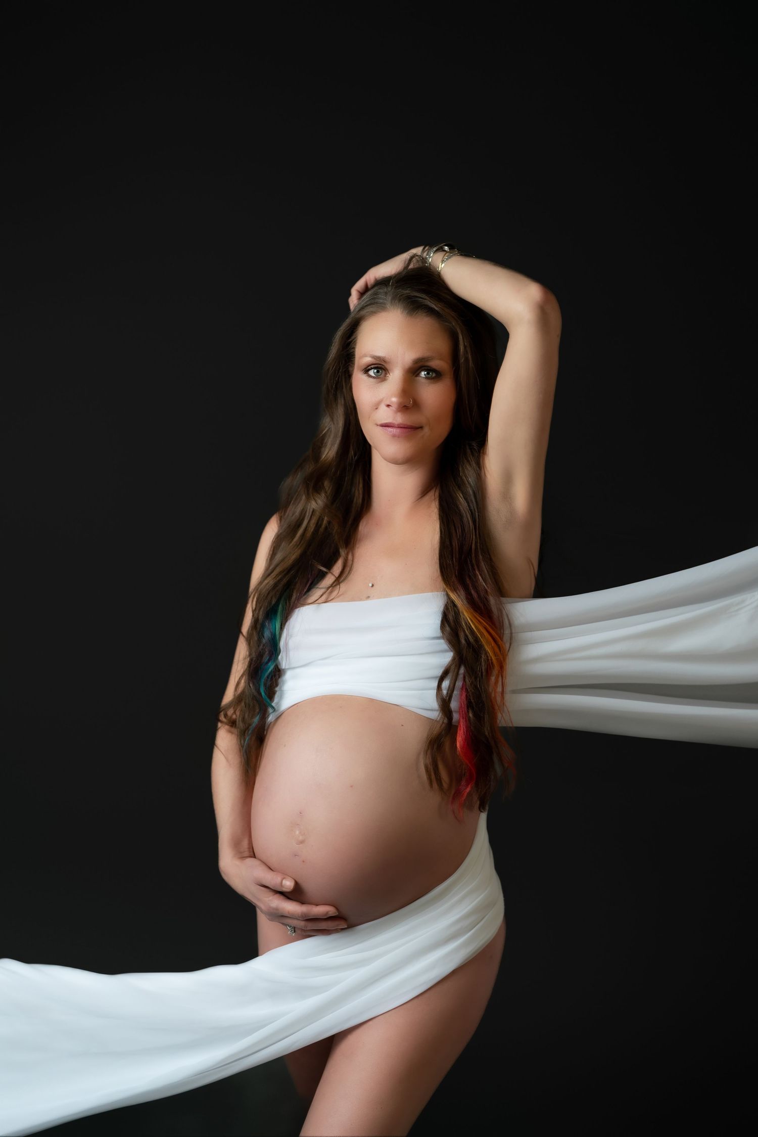Artistic maternity photos with flowing white fabric against black background.