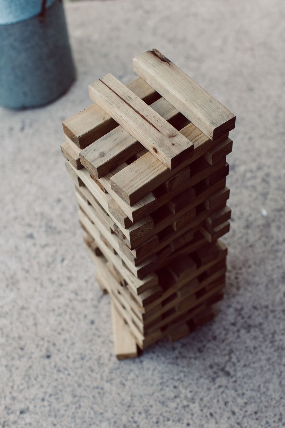 Small wooden blocks stacked in a geometric pattern creating an interlocking structure on a gray surface.