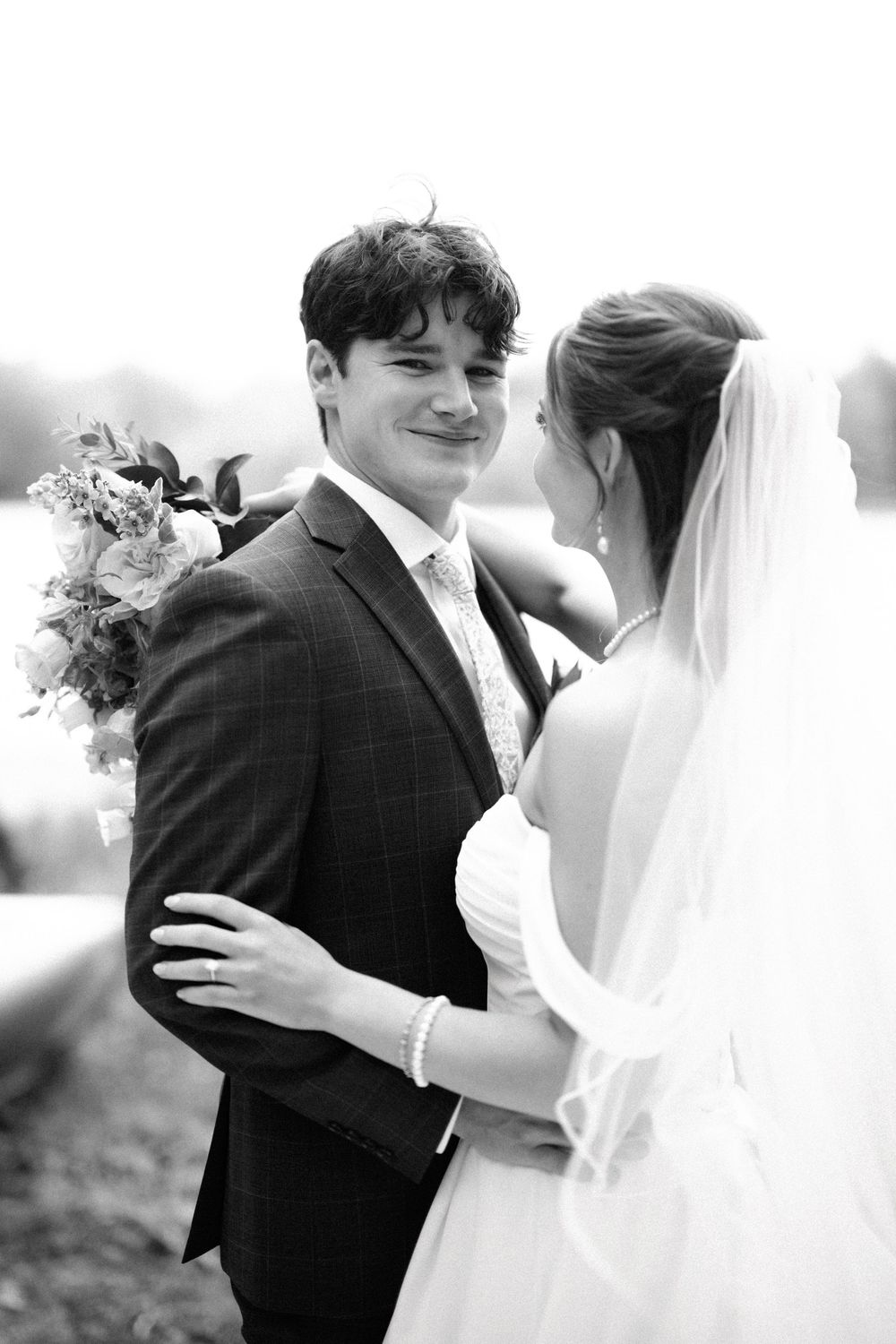 Black and white photo of a bride and groom sharing an intimate moment outdoors on their wedding day.