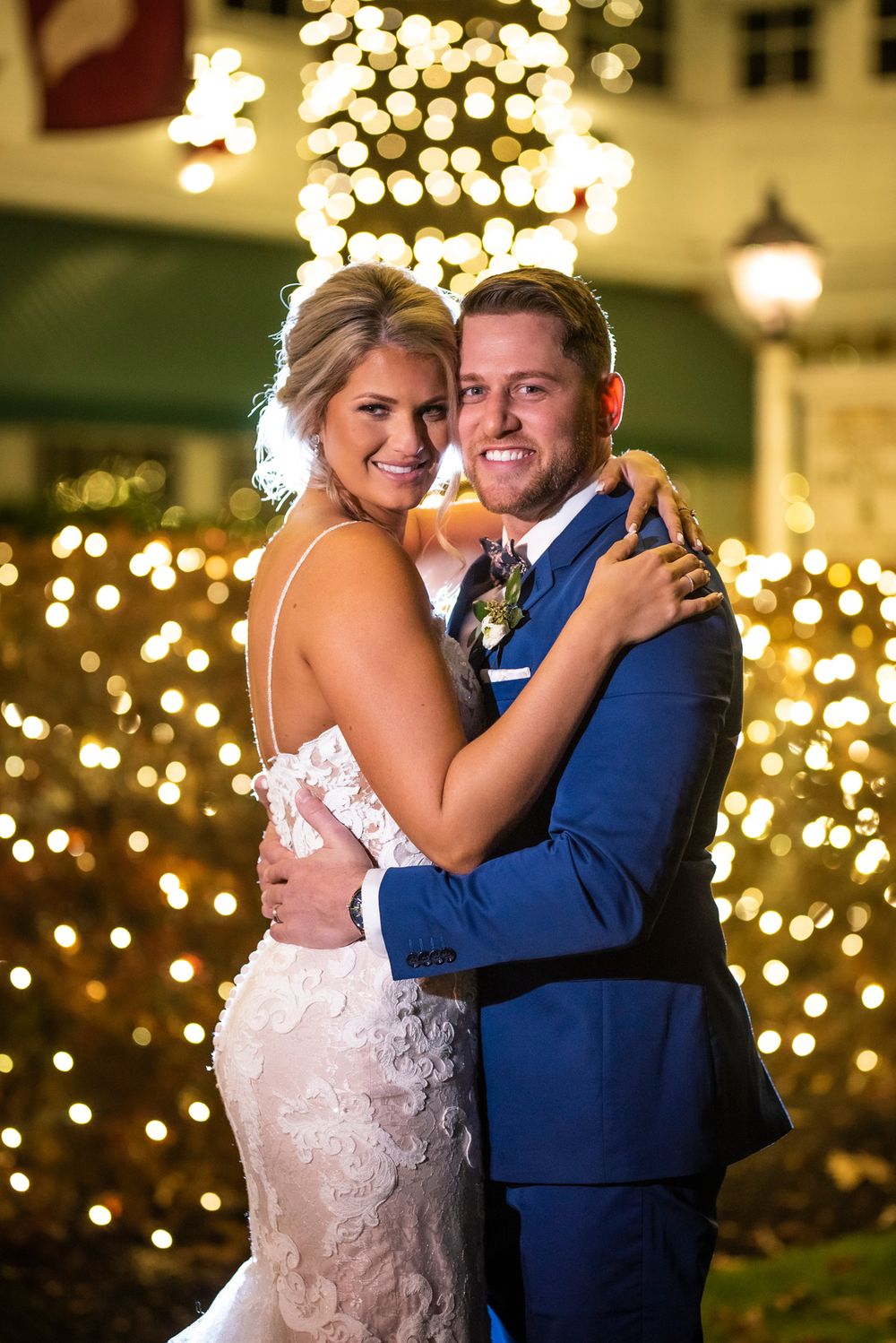 Couple dancing together at an evening reception with twinkling lights in the background.