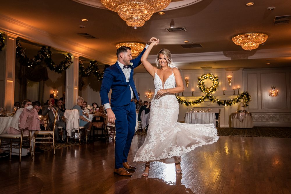Wedding reception dance floor with elegant chandeliers and guests dancing in a luxurious ballroom setting.