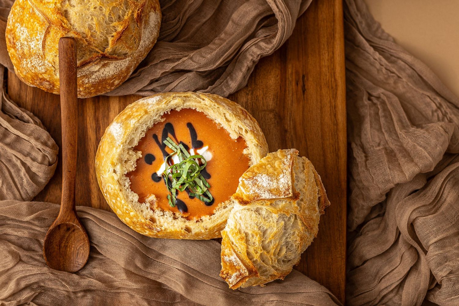 Overhead photo of a homemade bread bowl filled with tomato bisque soup and topped with balsamic made by Heartbakn in New Braunfels Texas.