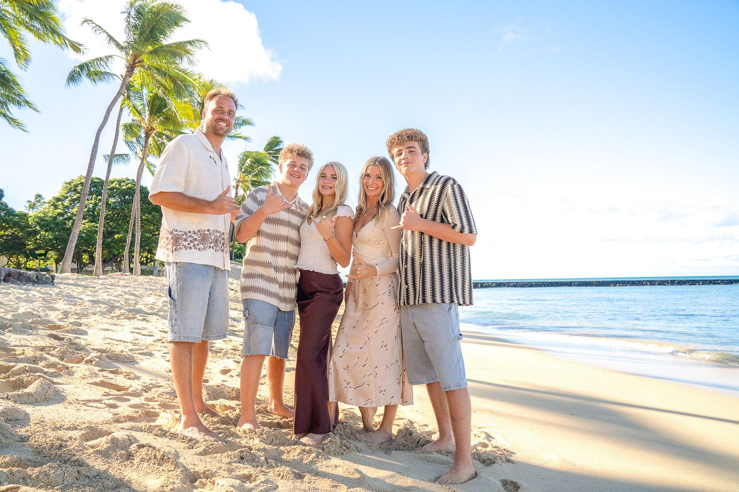 Group enjoying a tropical beach vacation with palm trees and ocean views in Hawaii during golden hour.