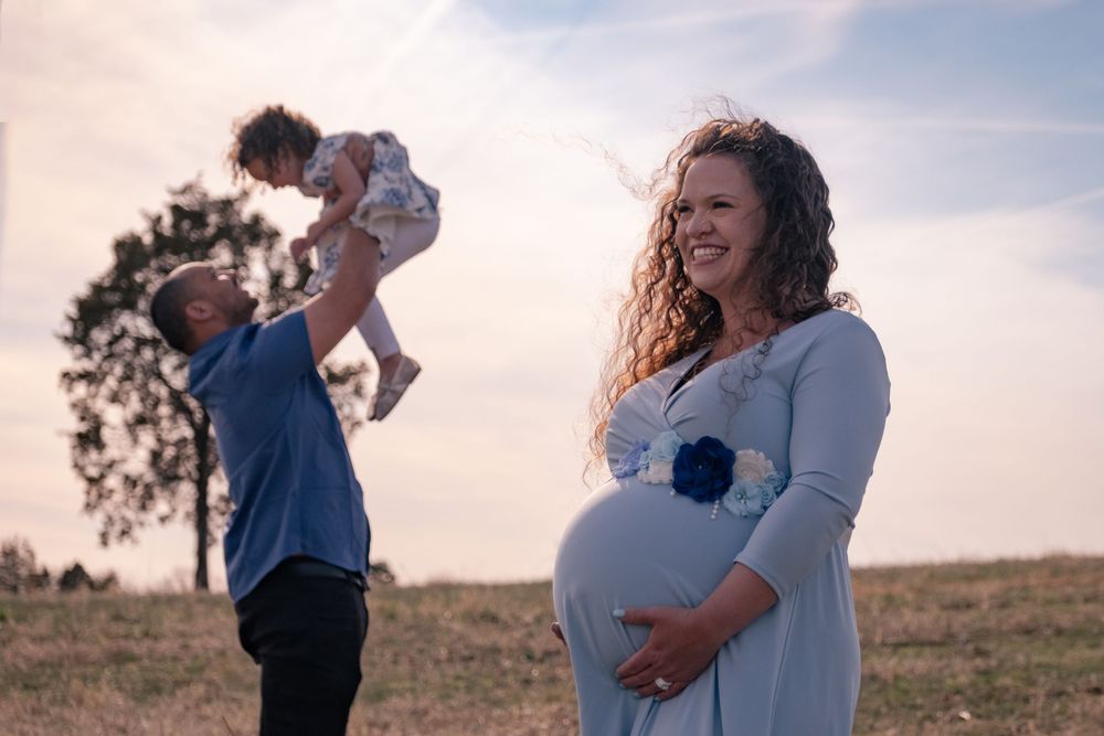 A couple shares tender moments together in a grassy field during sunset photography session.