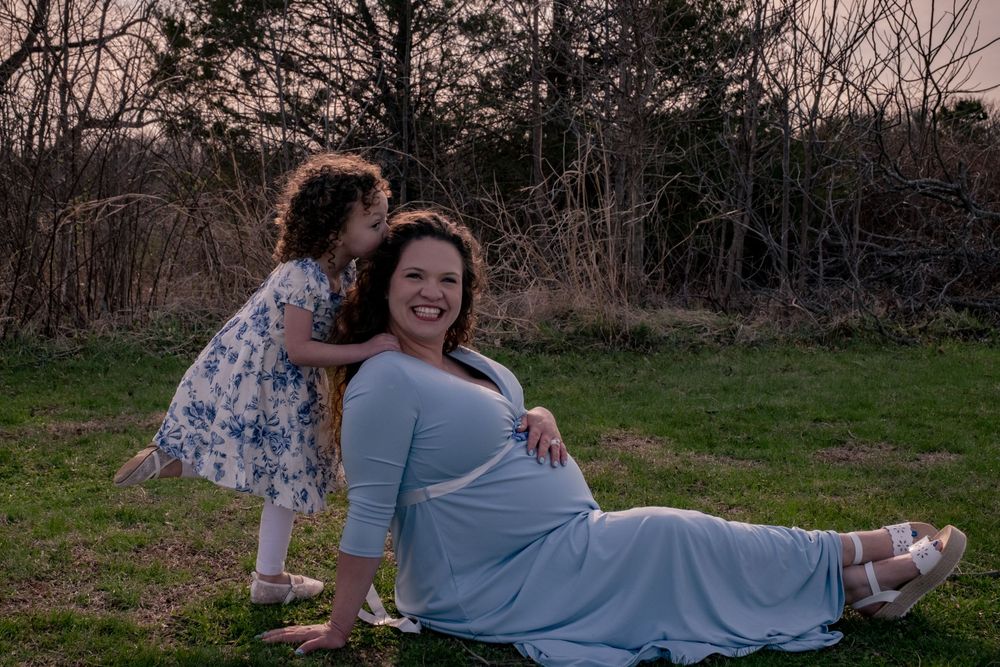 A series of romantic outdoor engagement photos showing a couple in casual blue outfits on grass at sunset.