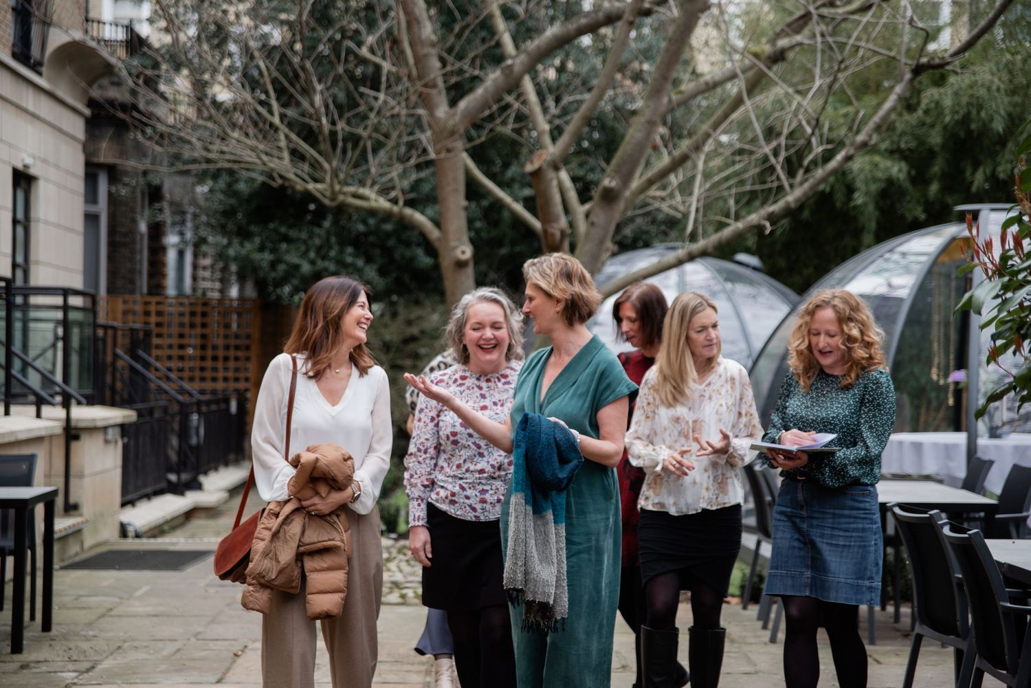 A group of people stand together outdoors while holding drinks and socializing at a casual gathering.