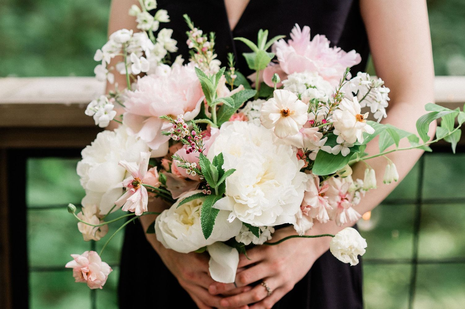 A delicate pink and white floral wedding bouquet with roses and greenery arranged in a romantic garden style.
