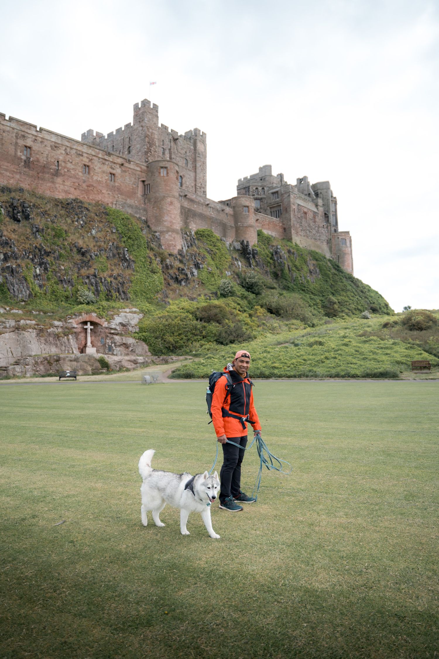 Homme avec son chien marchant au pied du château de Bamburgh