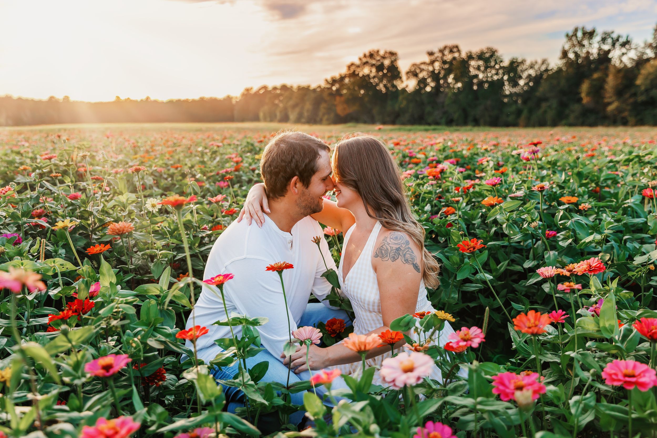 A romantic sunset photoshoot in a vibrant field of red and pink zinnias during golden hour.
