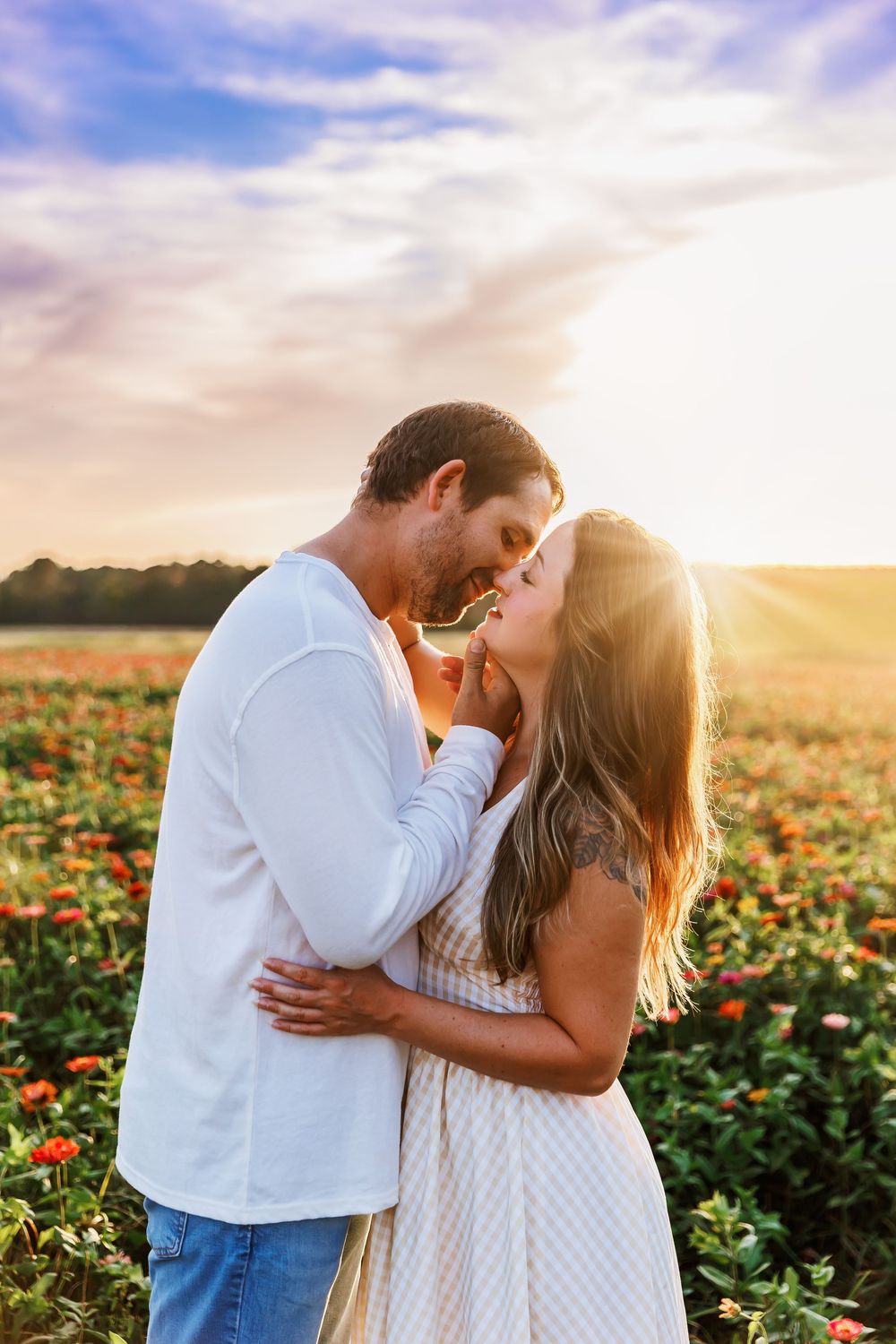 A tender moment captured between a couple in a blooming flower field at sunset.
