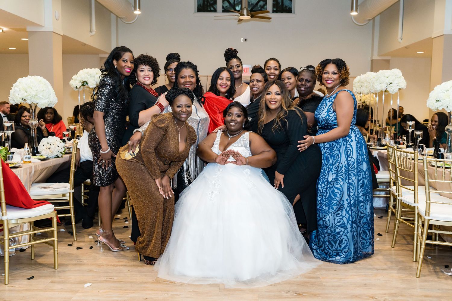 Wedding guests gather in a banquet hall during a celebration with blue dresses and white decor visible.