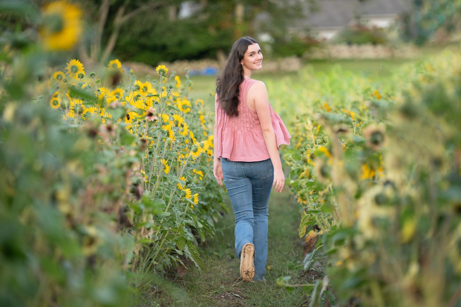 A woman in a blue dress relaxes in a garden with blooming pink flowers and green grass in the background.