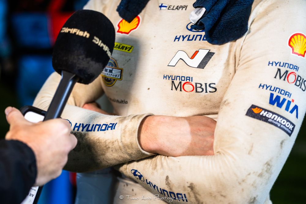 A microphone held up to interview someone wearing a Hyundai Mobis racing suit during a motorsport event.