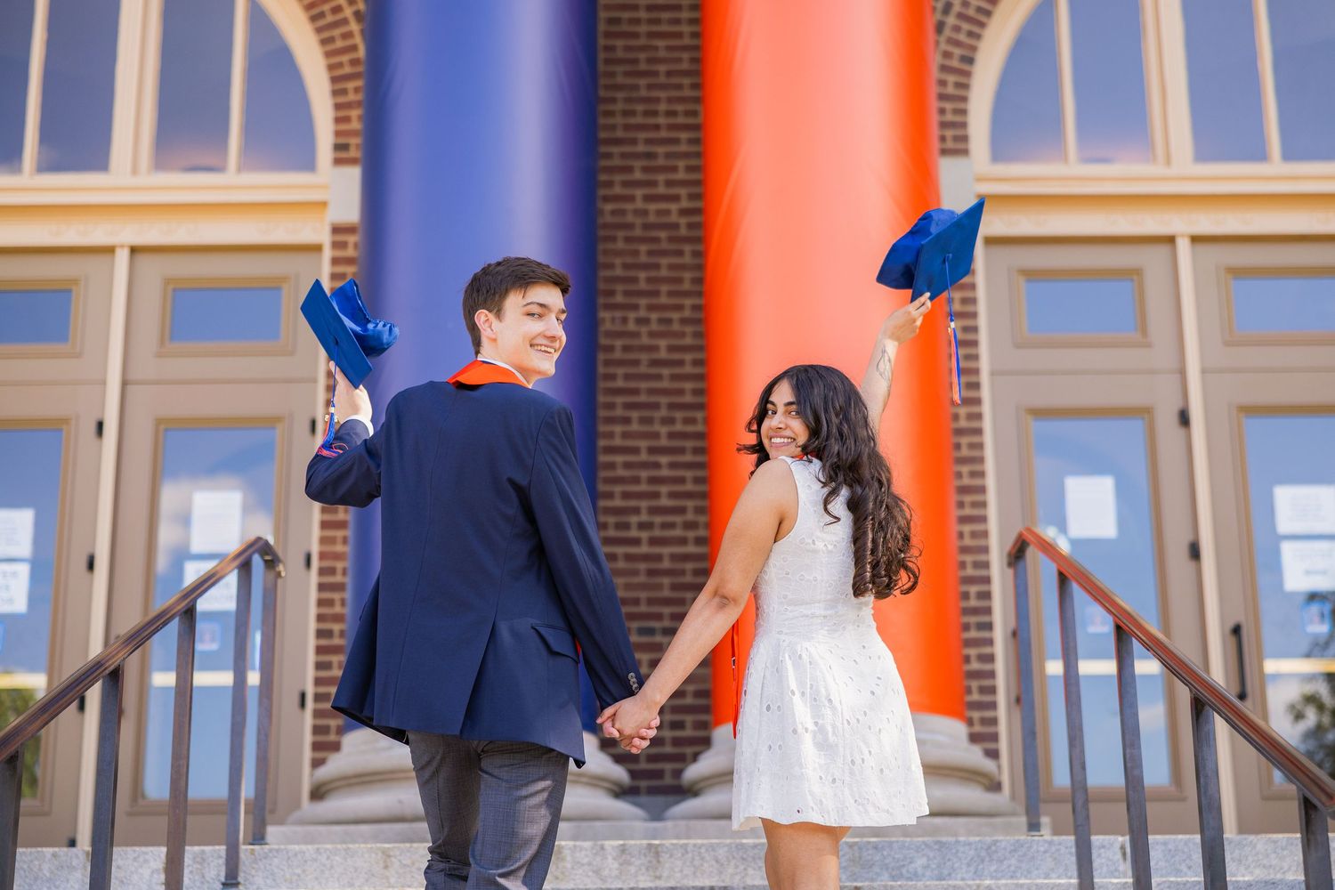 UIUC students graduating and walking up the Foellinger steps holding their caps up