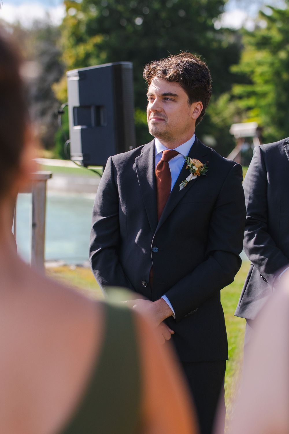 A man in a suit standing in a garden setting.