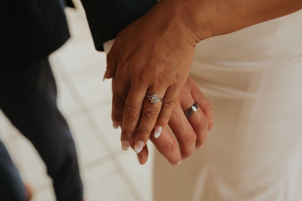 Close-up view of wedding rings on hands during a ceremony with soft lighting.