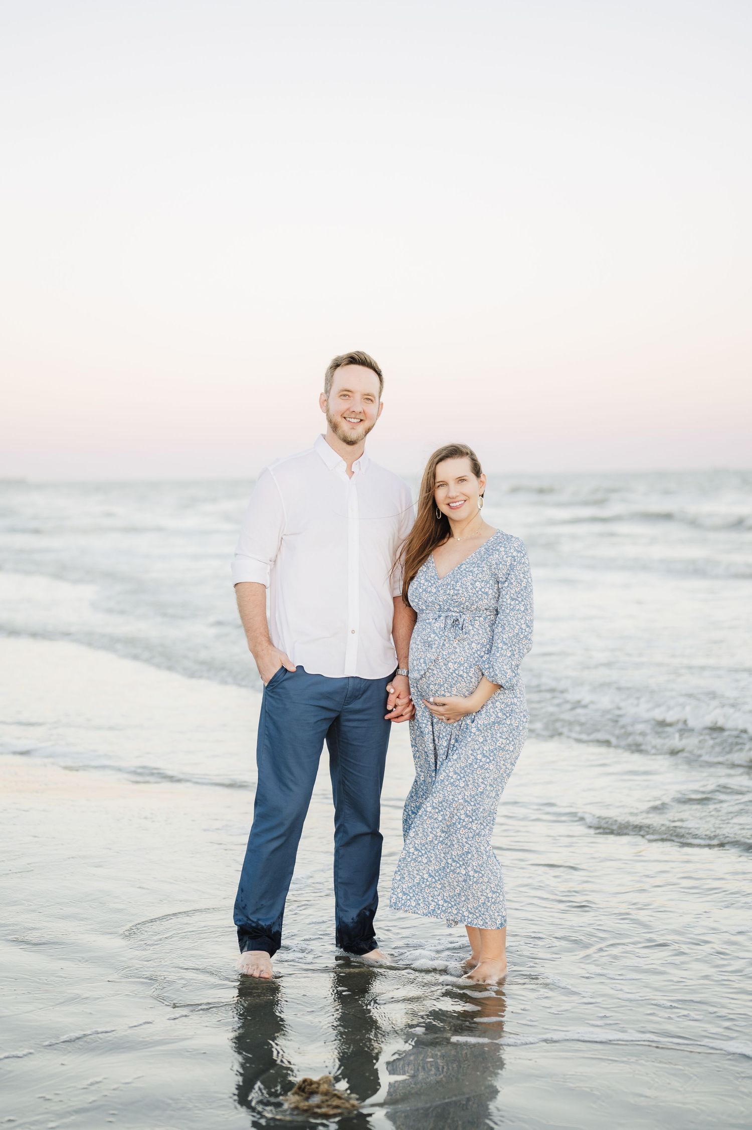 Couple enjoying a romantic moment together at the beach during sunset, standing in shallow ocean waves.