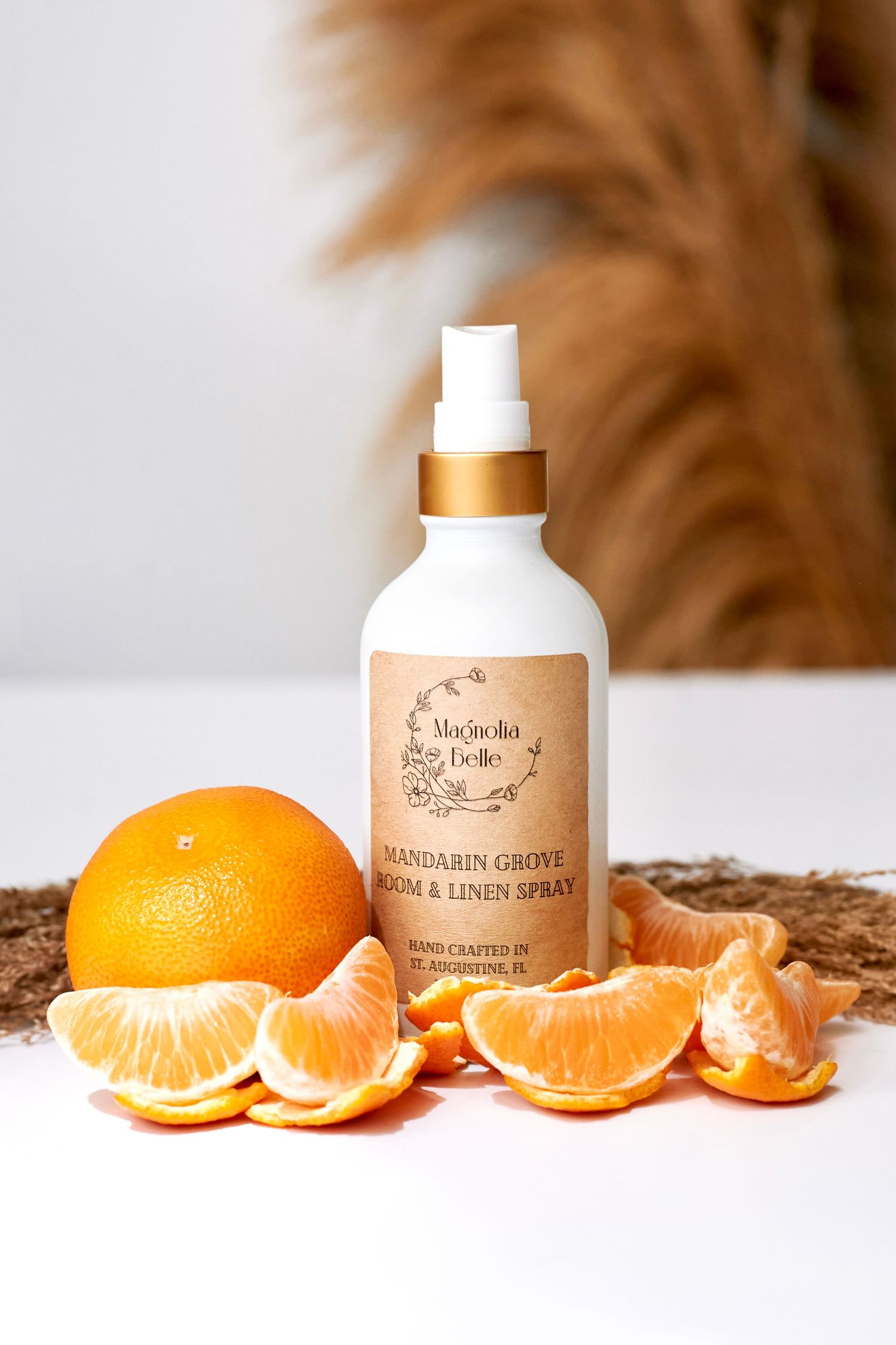Magnolia Belle Mandarin Grove Room & Linen Spray bottle surrounded by fresh oranges and mandarin slices.