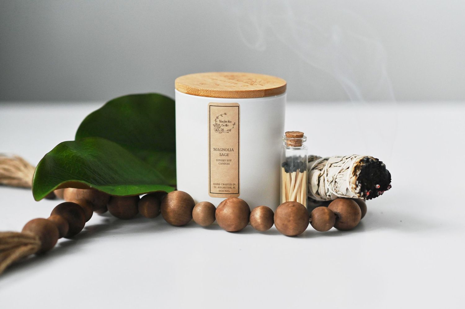Minimalist product photography of natural beauty products with hazelnuts and green leaves on white marble surface.
