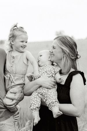 A series of black and white photos showing joyful interactions between a woman in black and a baby in light clothing.