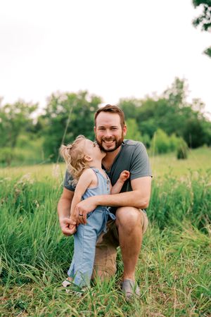 A playful family moment captured in a lush green field during a summer photoshoot.
