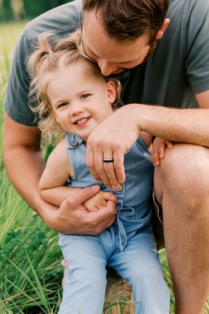 A series of candid outdoor photos showing tender moments between a parent and child sitting in green grass.