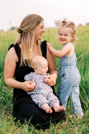 Sweet family interactions in a lush green field during a summer photoshoot with matching outfits.
