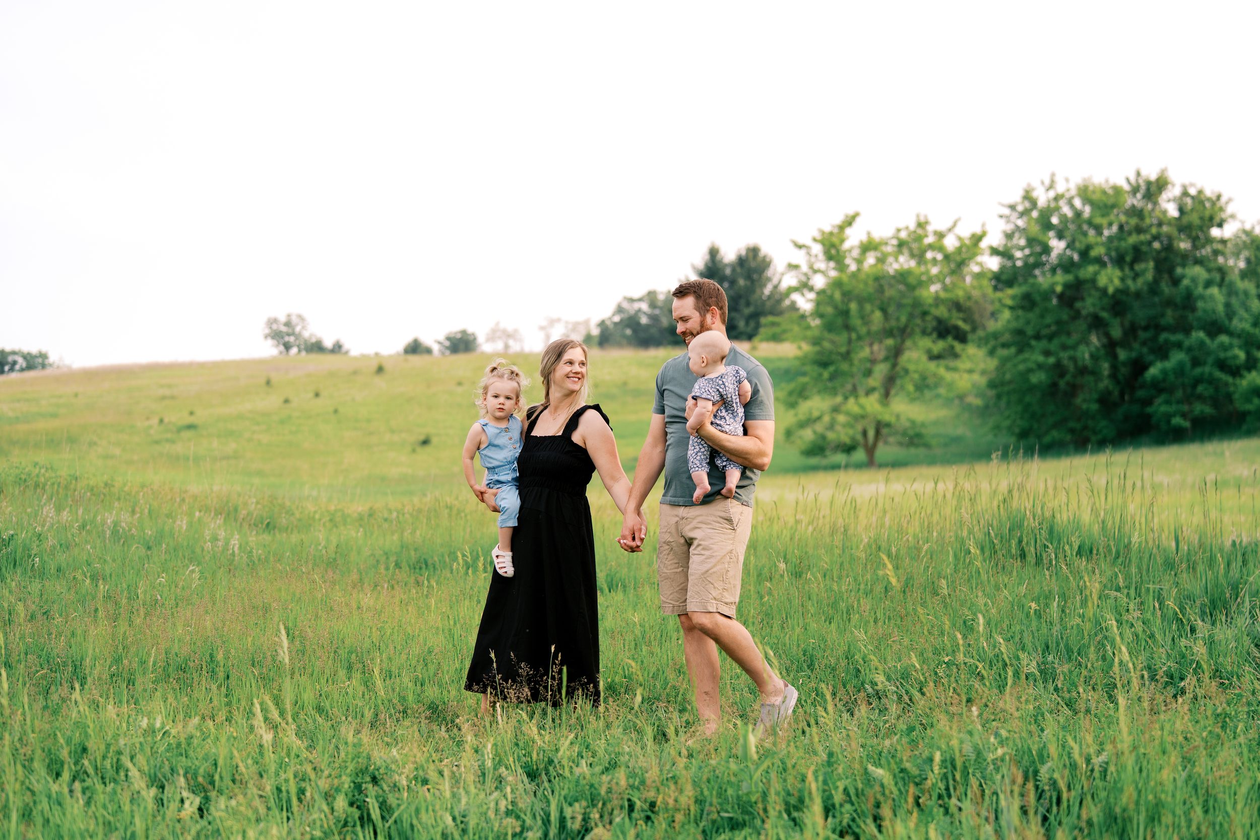 People walking through a lush green meadow on a sunny summer day.